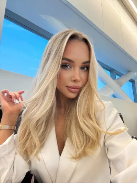 Anya taking a selfie while wearing a white elegant blouse